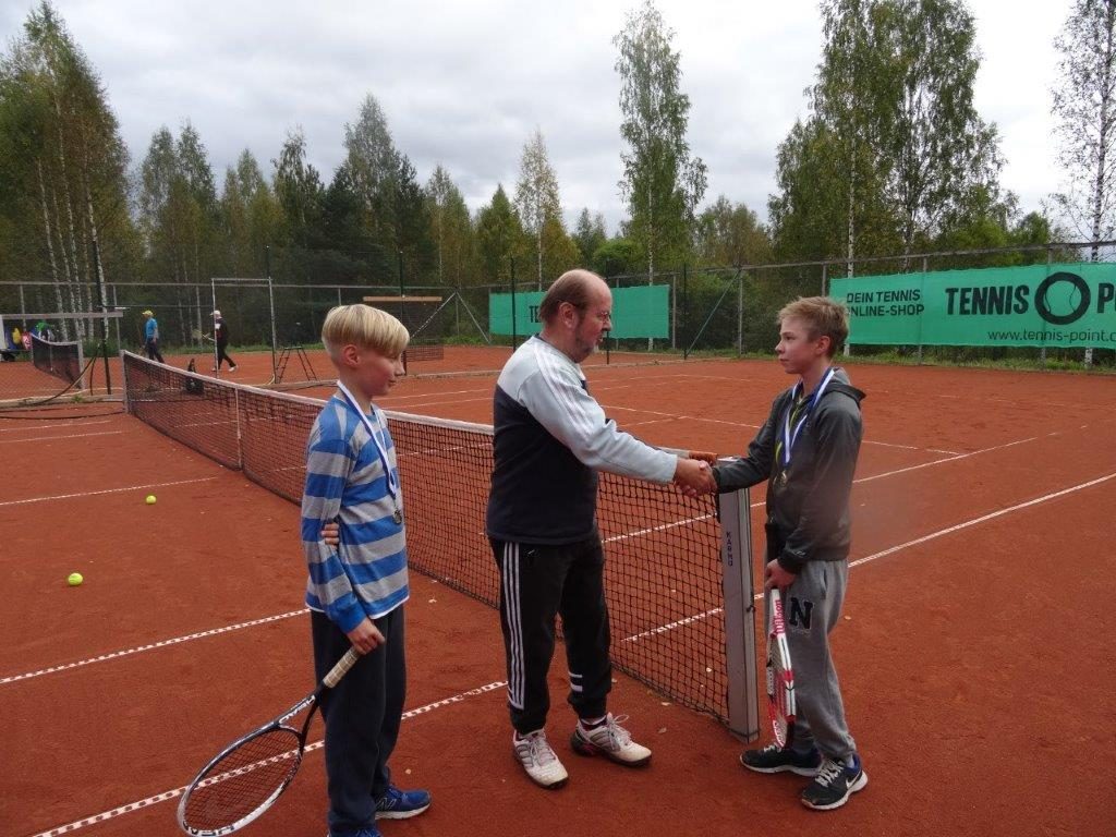 Tennisseuran puheenjohtaja Pekka Häyhä kättelee poikien voittajaa Artturi Kurikkaa
