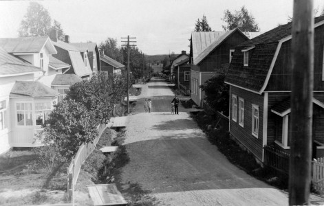 Kauppakatu piti saada kuivaksi. Kuva on otettu Salmelinin pajan katolta.  Ojien yli oli kaikilla liikkeillä hyvät sillat, joita pitkin pääsi liikkeen aidatulle pihalle ja ovelle – monesti vielä portista.  Kuvan ottaja voi olla aivan vieressä lähellä asunut Hyvönen tai Frans Kalin – kuva otettu vuosien 1924-1926 välillä. Näitä kortteja voi vielä joitakin olla löydettävissä.