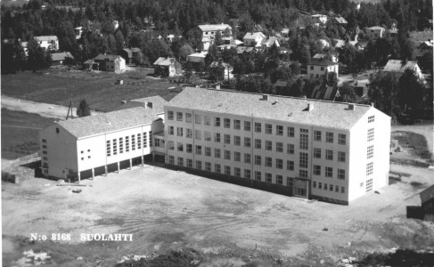 Kotitalousnäyttelylle keskeisen koulurakennuksen viereen Suolahti sai 1952 uuden urheilukentän ja harjoitteluhiekkakentän, mikä siivittikin pitkäksi aikaa kauppalan urheilua. Mutapohjaan suunniteltiin ensin uutta kenttää, mutta sekin katsottiin liian kaukanaolevaksi, kuten entinenkin kenttä Äänekoskentien varrella Alkulassa. Honkalaan, Pässinmäen sorakuoppaan tasoitettiin samaan aikaan toinen hiekkakenttä. Tämä koulun postikortti on varsin harvinainen Karhumäen ilmakuva, vaikka näitä uskoisi aikanaan olleen paljonkin liikenteessä.
