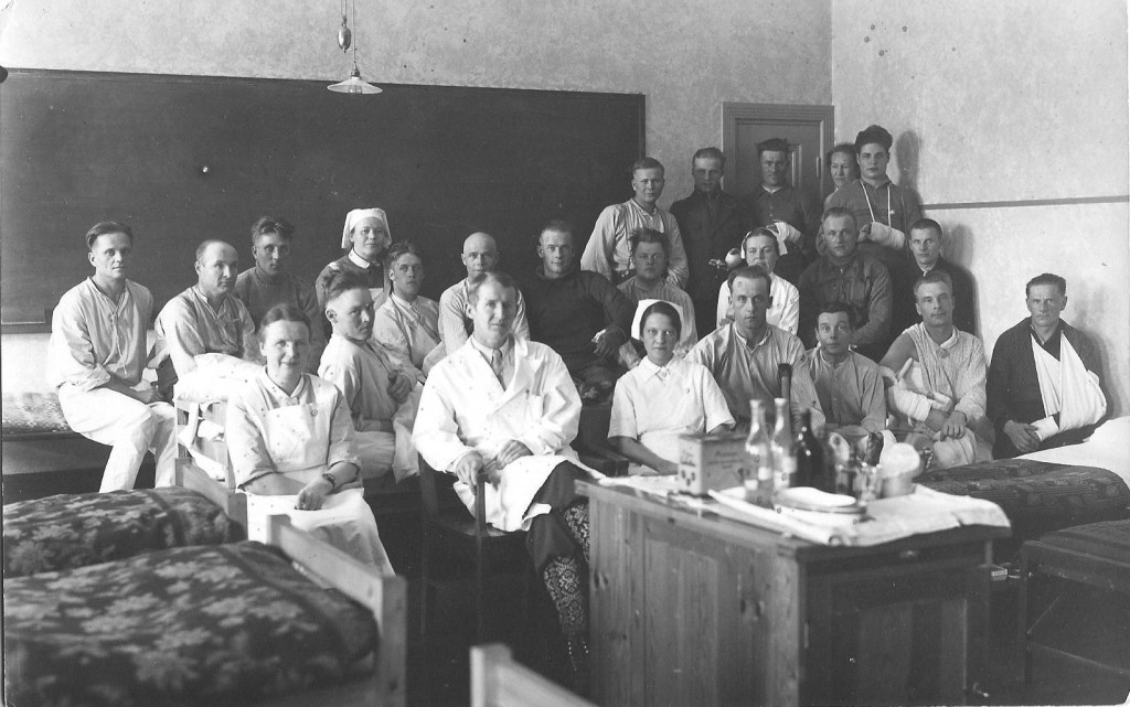  Sotasairaalan huone 7 potilaineen. Huone oli hoitaja Holopaisen vastuulla ja lääkärivastuuta kantoi norjalainen vapaaehtoinen Olav Farnes, jolla on norjalaisperinteiset sukat jalassaan. Jo kolmikymppisiä norjalaislääkäreitä kutsuttiin tohtoreiksi. 